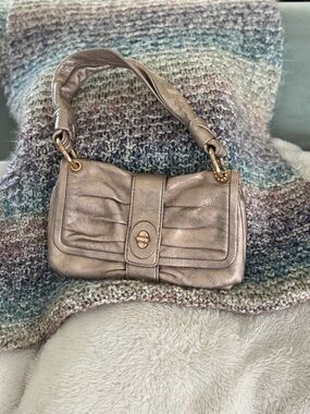 Vintage Coach rose gold metallic shoulder bag with magnetic closure.